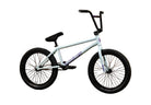 A white BMX bike with black handlebars, seat, and tires, featuring the Sunday brand logo on the frame, set against a brown cardboard backdrop with the Sunday logo printed on the wall.