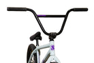 A BMX bicycle with a white frame and black handlebars, featuring purple 'Sunday' branding on the frame and top tube, set against a background of stacked cardboard boxes with the word 'Sunday' printed in black.