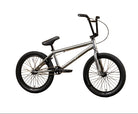 A silver BMX bicycle with black tires, handlebars, and saddle, displayed against a yellow wall with the brand name 'Sunday' printed on it.